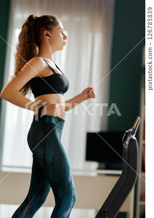 Young woman running on a treadmill indoors Young woman running on a treadmill indoors 126785839