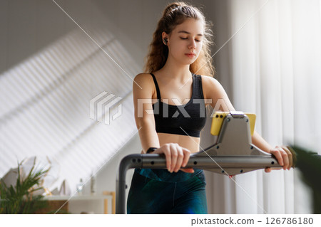 Young woman running on a treadmill indoors Young woman running on a treadmill indoors 126786180