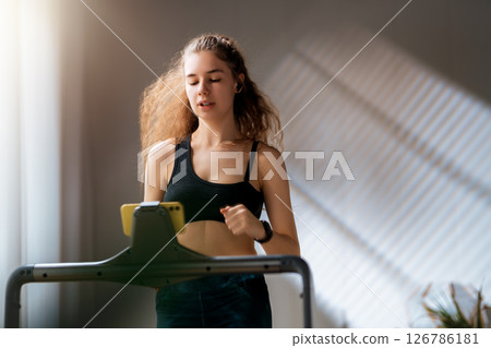 Young woman running on a treadmill indoors Young woman running on a treadmill indoors 126786181