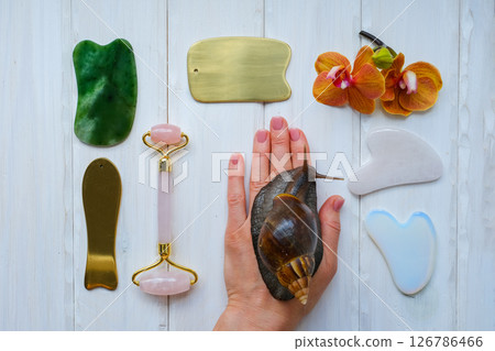 Spa concept gua sha massage body and face care and snails achatina on hand, flat lay. High quality photo 126786466