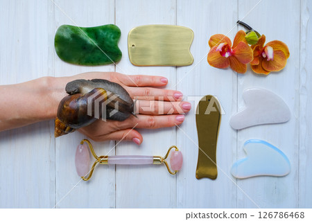 Spa concept gua sha massage body and face care and snails achatina on hand, flat lay. High quality photo Spa concept gua sha massage body and face care and snails achatina on hand, flat lay. High quality photo 126786468