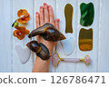 Two achatinas on hand and facial massage kit. Face roller and guasha massager made from natural stones and metal, flat lay. High quality photo Two achatinas on hand and facial massage kit. Face roller and guasha massager made from natural stones and metal, flat lay. High quality photo 126786471