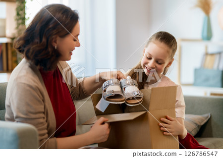 Mother and daughter are unpacking cardboard Mother and daughter are unpacking cardboard 126786547