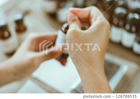 Shot of mature perfumer adding extra essential oil Shot of mature perfumer adding extra essential oil 126789535
