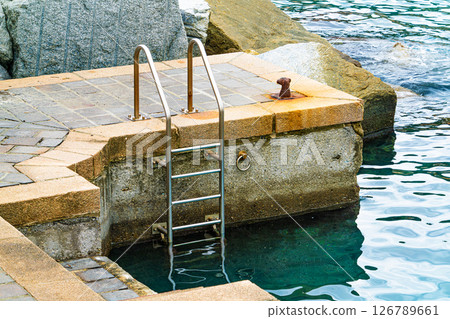 Stone Dock with Ladder Leading into Sea Water 126789661