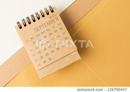 Blank desk calendar for September 2025 on brown tone background. 126790447