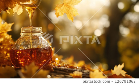 Maple Syrup Pouring into Jar Among Autumn Leaves 126791062