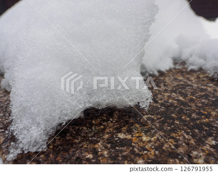Close-up of fresh snow resting on a textured rock surface, capturing the intricate detail of icy crystals. Perfect natural winter texture for backgrounds or seasonal designs. Close-up of fresh snow resting on a textured rock surface, capturing the intricate detail of icy crystals. Perfect natural winter texture for backgrounds or seasonal designs. 126791955