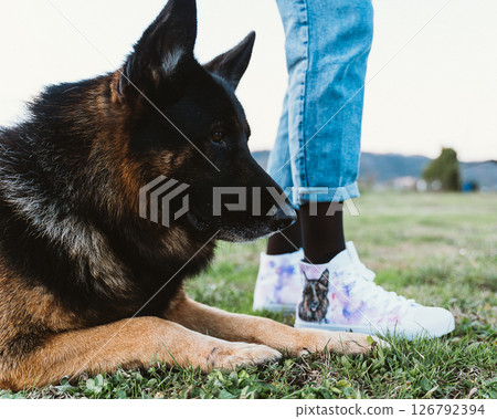 German Shepherd Relaxing with Human Companion Outdoors German Shepherd Relaxing with Human Companion Outdoors 126792394
