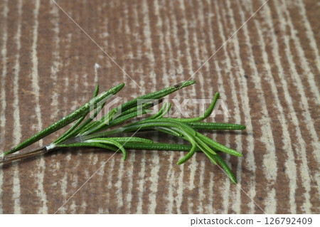 Dry organic background or texture of rosemary leaves. Healthy food concept . a wooden spoon with rosemary 126792409