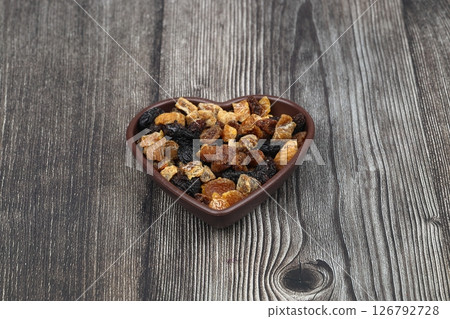 Mix of nuts and dried fruits in wooden bowl isolated on a wooden background. 126792728