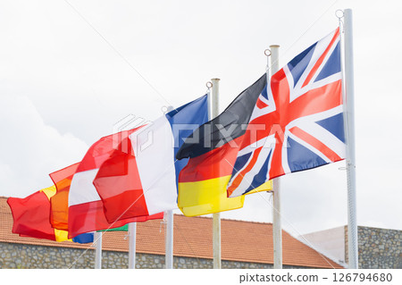 Flags of European nations visible against a cloudy sky in an open space 126794680