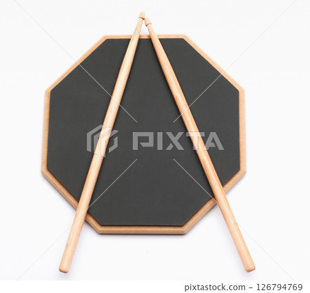 Drums dark gray rubber pad and pale wooden sticks isolated on white. Music training education kit. 126794769