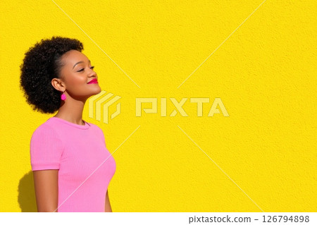 Woman in Pink Against Bright Yellow Wall Woman in Pink Against Bright Yellow Wall 126794898