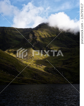 Lough Callee landscape showcasing rugged mountains, serene waters, and dramatic sky in Ireland during morning light. Lough Callee landscape showcasing rugged mountains, serene waters, and dramatic sky in Ireland during morning light. 126795417