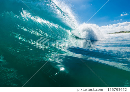 Powerful barrel wave with crystal clarity under a bright blue sky on sunny day. Powerful barrel wave with crystal clarity under a bright blue sky on sunny day. 126795652