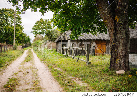 Dirt road leading to an old wooden barn in the countryside Dirt road leading to an old wooden barn in the countryside 126795947