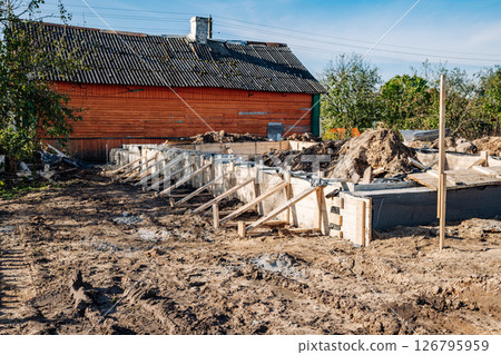 Building strip foundation for new house next to old wooden house 126795959