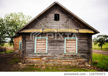 Old abandoned wooden house falling apart in countryside landscape 126795973