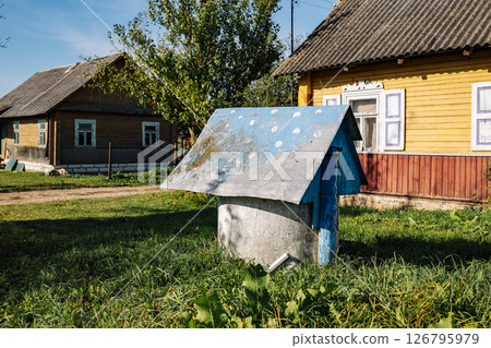 Old Water Well Standing Near Traditional Wooden Houses In Village 126795979