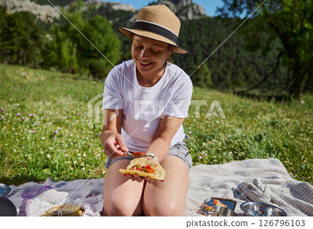 Happy Family Enjoying a Scenic Outdoor Picnic While Preparing Tacos 126796103