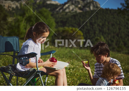 Family Enjoying Outdoor Picnic in Nature Amidst Scenic Mountain Views Family Enjoying Outdoor Picnic in Nature Amidst Scenic Mountain Views 126796135