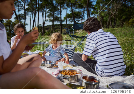 Family Enjoying Picnic Outdoors Amidst Scenic Nature 126796148