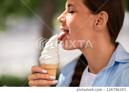 Ice cream Woman Summer Enjoy: Young woman licks soft serve ice cream cone outside on a warm summer day. Ice cream Woman Summer Enjoy: Young woman licks soft serve ice cream cone outside on a warm summer day. 126796203