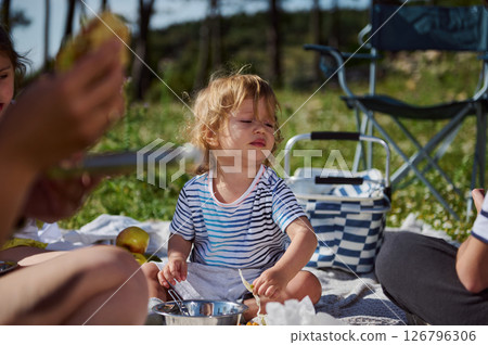 Little Child Enjoying Family Picnic in Scenic Outdoor Setting Little Child Enjoying Family Picnic in Scenic Outdoor Setting 126796306