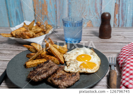 Gourmet homemade burger with a perfectly fried egg and seasoned potatoes, a hearty meal Gourmet homemade burger with a perfectly fried egg and seasoned potatoes, a hearty meal 126796745