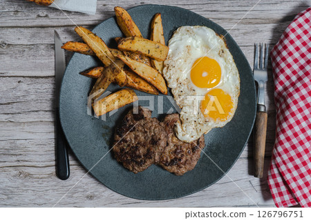 Enjoying delicious homemade hamburgers with fried eggs and potatoes Enjoying delicious homemade hamburgers with fried eggs and potatoes 126796751