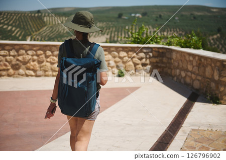 Traveler with Backpack Exploring a Scenic Mountain Landscape with Olive Groves 126796902