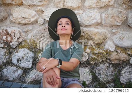 Woman Relaxing Outdoors Against Historic Stone Wall Background 126796925