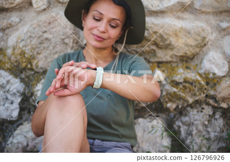 Woman Resting Outdoors Checking Her Wristwatch During an Adventure 126796926