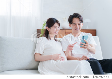 Pregnant wife and husband looking at smartphone 126797335