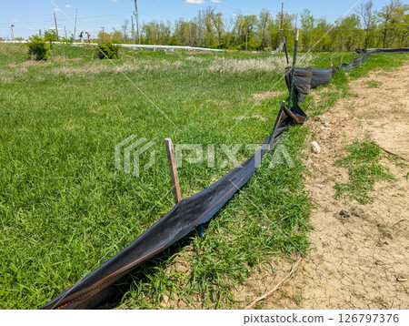 Sagging and damaged stormwater fabric silt fence at a construction site 126797376