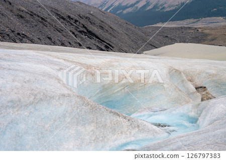 Crevasse in the ice from melting at Athabasca Glacier in Jasper National Park with cloudy sky Crevasse in the ice from melting at Athabasca Glacier in Jasper National Park with cloudy sky 126797383