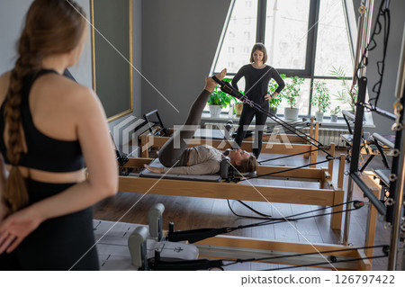 Woman training pilates on the reformer bed. Reformer pilates studio machine for fitness workouts in gym. Fit, healthy and strong authentical body. Fitness concept 126797422