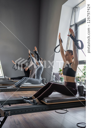 Woman training pilates on the reformer bed. Reformer pilates studio machine for fitness workouts in gym. Fit, healthy and strong authentical body. Fitness concept 126797424