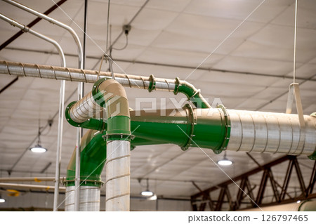 Industrial HVAC metal Pipe header with multiple connections in a production facility with a coating of dust. 126797465