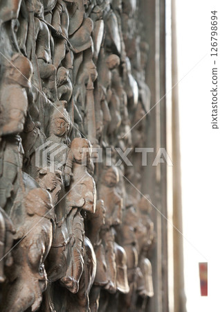 A wooden door with lots of human faces carved into it 126798694