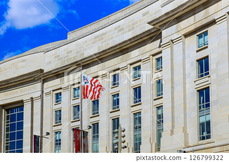 19 April 2025 Washington D.C US American flag flutters by Reagan Building, showcasing Washington D.C. architectural beauty. 19 April 2025 Washington D.C US American flag flutters by Reagan Building, showcasing Washington D.C. architectural beauty. 126799322