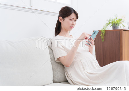 Pregnant woman using a smartphone (worrying/thinking) Pregnant woman using a smartphone (worrying/thinking) 126799843