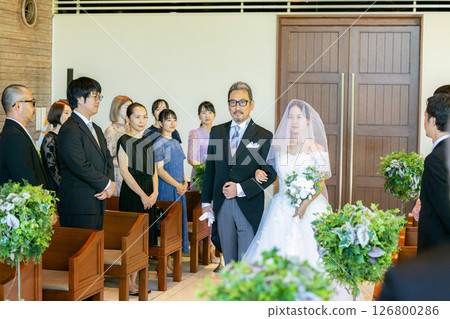 Bride and groom walking down the aisle with their father 126800286