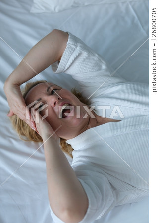 woman doing facial massage lying on white sheet massaging forehead chin rubbing hands youth beauty adult woman taking care of herself at home european female in white coat woman doing facial massage lying on white sheet massaging forehead chin rubbing hands youth beauty adult woman taking care of herself at home european female in white coat 126800705