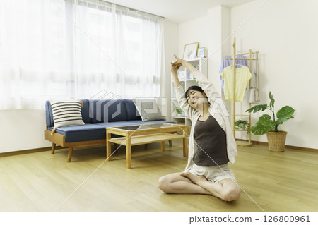 A young woman stretching in the living room 126800961
