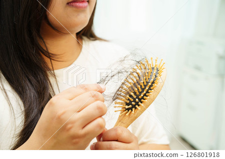 Asian woman have problem with long hair loss attach to comb brush. 126801918