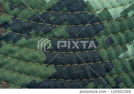 Close up of textured camouflage military uniform of soldier. In military use, camouflage is an appearance designed to hide soldiers and equipment on the ground. Close up of textured camouflage military uniform of soldier. In military use, camouflage is an appearance designed to hide soldiers and equipment on the ground. 126802260