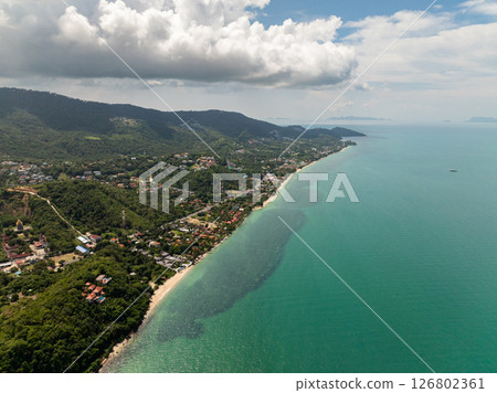 Tropical coastline with green hills and clear waters stretching to the horizon under a dramatic cloudy sky. Koh Samui, Thailand. 126802361