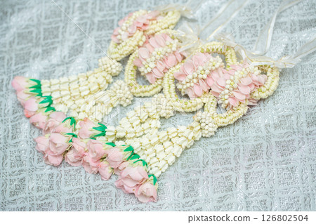 Beautiful Thai-style jasmine garland on a silver cloth background with an ancient Thai pattern. Beautiful Thai-style jasmine garland on a silver cloth background with an ancient Thai pattern. 126802504